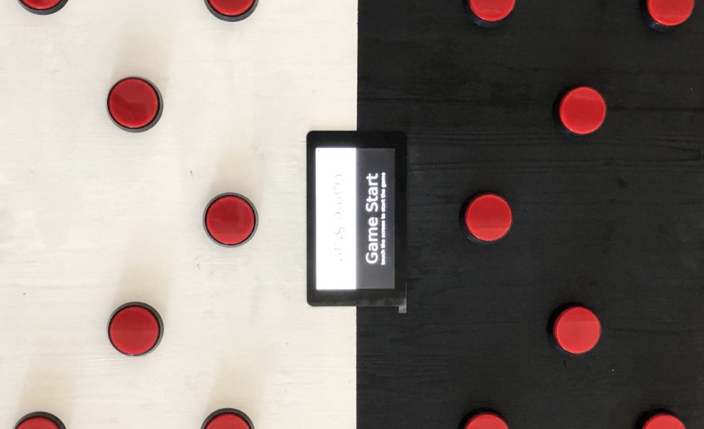 Bild des Monitors in der Mitte des Klatschboards mit Anzeige für Game Start, drumherum Buttons
